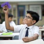 Boy throwing paper airplane in classroom